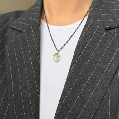Person wearing a pinstripe suit and pearl necklace